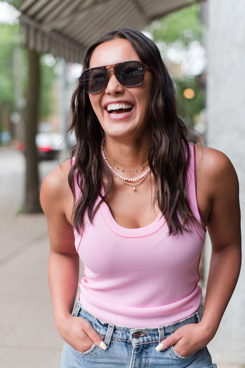 Woman in the city wearing pink opal necklace and gold hoops