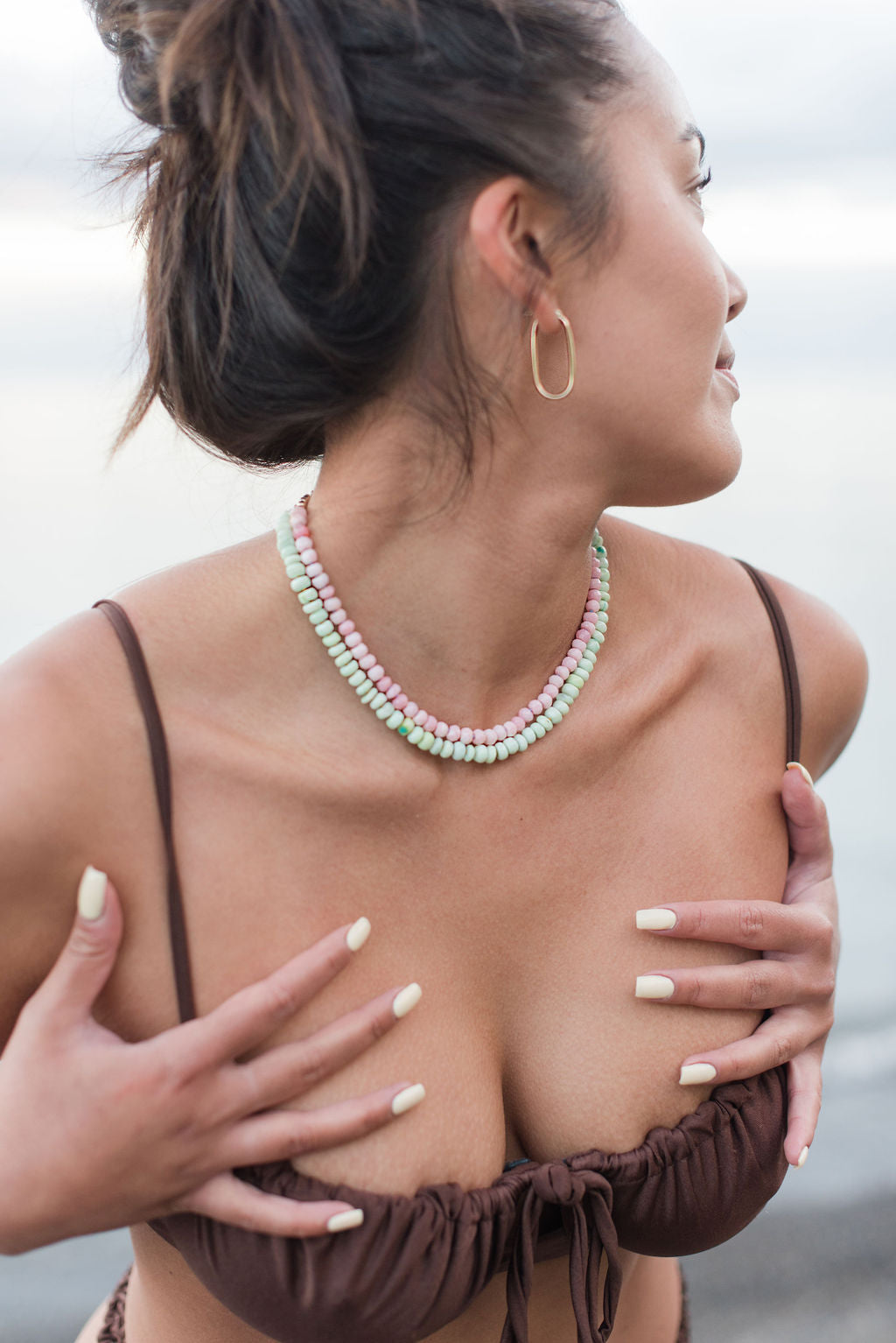 Woman on beach with green opal and pink opal necklaces